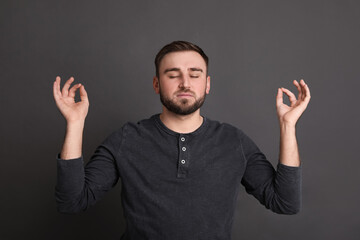 Young man meditating on grey background. Personality concept