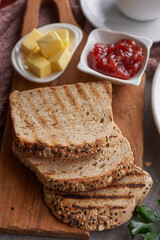 Traditional english breakfast with toast, butter, jam on a wooden board.