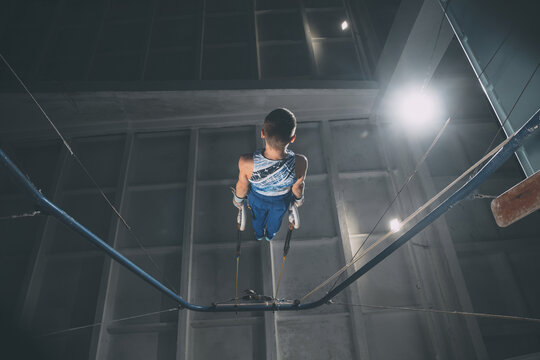Little male gymnast training in gym, flexible and active. Caucasian fit little boy, athlete in sportswear practicing in exercises for strength, balance.