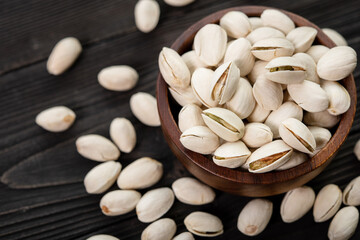 Bowl with pistachios on a wooden table. (selective focus; close-up shot)