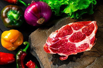 Juicy marble steak and fresh vegetables lie on the stone. Picnic set