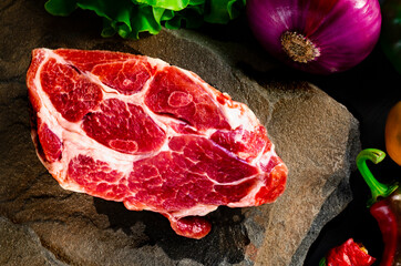 Juicy marble steak and fresh vegetables lie on the stone. Picnic set