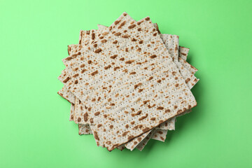Stack of traditional matzos on green background, top view