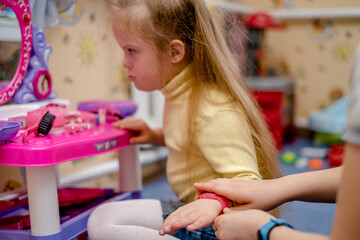Development and education of a small child with down syndrome. Little girl with down syndrome plays princess in the children's room.