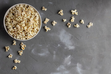 Popcorn in white bowl on grey table. Top view with copyspace