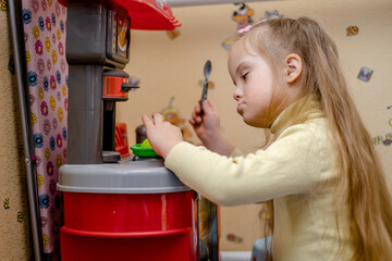 Development and education of a child with down syndrome. A game of cheating. A girl with down syndrome pretends to play pigmentation of food.