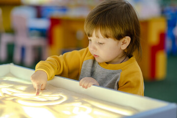 Creative child development. Baby draws sand on glass. Early development of children. Development of...