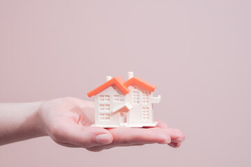 Fototapeta na wymiar Hand holding toy house miniature. Rent, mortgage and real estate concept with copy space