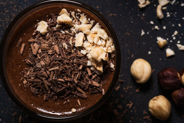 Homemade dark chocolate mousse with hazelnut in glasses on dark grey table