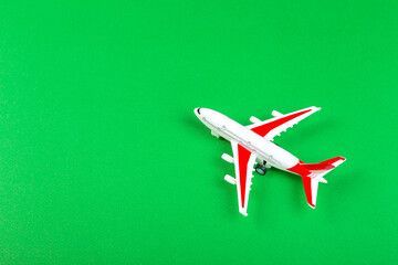 Fototapeta na wymiar plastic model of an airplane with red wings. tourism and travel concept. green background top view