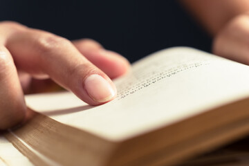 Closeup index finger place at the sentence in the old book to repeat the point of content while reading and searching information in the novel
