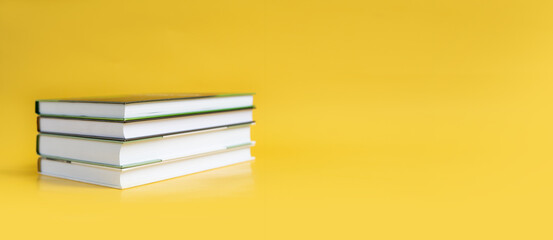 A stack of books on a yellow background. The books are on a plain background with space for...