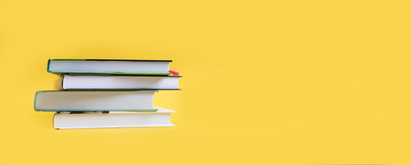 A stack of books on a yellow background. The books are on a plain background with space for writing. Composition of a reading person.