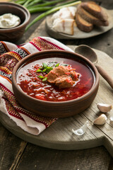 Borscht - Traditional Ukrainian dish.  Vegetable soup made from beets, potatoes, cereals and boiled meat, and  slices of rye bread in a ceramic bowl on a wooden kitchen table. Russian  food cuisine