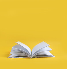 open book on a yellow background. The book lies on a plain background with space for writing. Composition of a reading person.