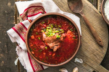 Borscht - Traditional Ukrainian dish.  Vegetable soup made from beets, potatoes, cereals and boiled meat, and  slices of rye bread in a ceramic bowl on a wooden kitchen table. Russian  food cuisine