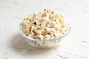 popcorn in a transparent glass bowl on white table