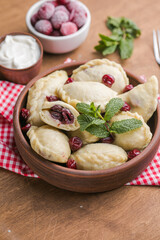 Pierogi with cherries. c. Traditional Ukrainian food. Cooked and served with sour cream and berry