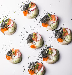 Sushi donuts with salmon, cucumber and radish on white background top view. Hybrid Foods.