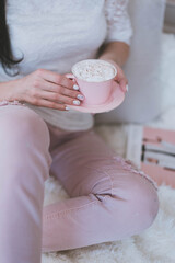 female hands with manicure hold a pink mug with coffee
