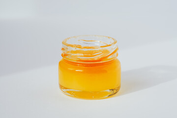 Yellow golden honey in glass jar, closeup. Sunny atmospheric minimalistic apiculture concept