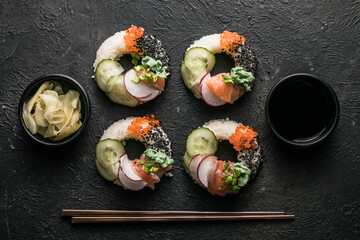 Sushi donuts with salmon, cucumber and radish on dark background top view. Hybrid Foods.