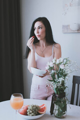 Obraz na płótnie Canvas brunette girl eating strawberries from a white plate