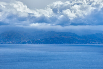 Fototapeta na wymiar the coast of Calabria seen from the Strait of Messina with big clouds unexpected for a thunderstorm