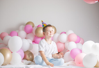 Fototapeta na wymiar Little boy in white balloons . Small child with party balloons, celebration. Birthday, happiness, childhood, look.