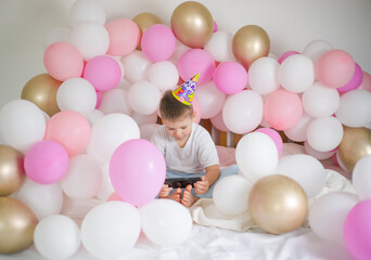Fototapeta na wymiar Cute kid boy smiling and taking selfie photo on cellphone with balloon. Birthday party