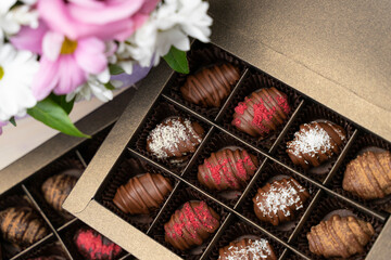 Fototapeta na wymiar Congratulatory Chocolate Box assorted with bouquet of flowers. Handmade chocolates candy - gift for celebration