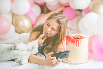 Lovely lady in pajama making selfie in her bedroom using phone and kiss  her dog. Indoor portrait  girl with baloons in morning. Husband surprising his wife.