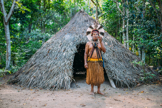 Shaman of the Patax&oacute; tribe, wearing feather headdress and smoking a pipe. Brazilian Indian looking at the camera