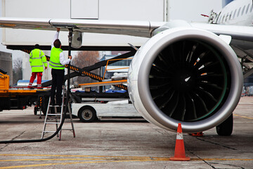 Refueling the plane. Airport handling. A male worker on the stairs connects the hose. Service,...