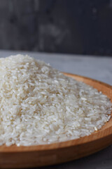 Rice in a wooden bowl on a gray background, raw, natural food with a high protein content.