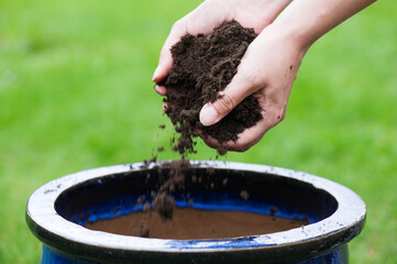 Gardener adds mulch to a pot and prepares to plant some flowers.
