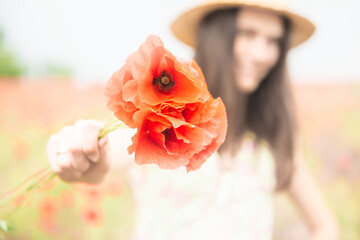 Young beautiful happy woman with bunch of poppy on field, summer outdoor.