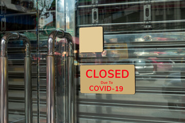 Close-up on a closed sign in the window of a shop displaying the message "Closed due to Covid-19"