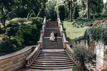 A romantic walk for the bride and groom in the garden of the mansion. Outdoor photo session.