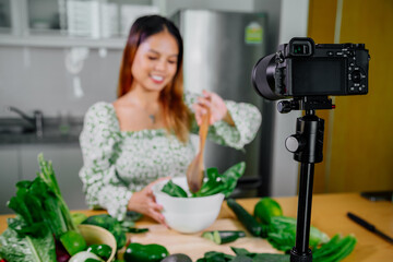 Asian woman blogger or content creator cooking and recording video camera. showing healthy food while recording with camera at kitchen.