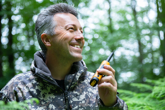 Smiling mature man walking and hiking in mountain forest and using radio set. Male spring outdoor portrait. - Powered by Adobe