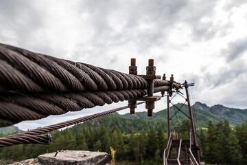 Close-up on a metal binding cable going in perspective to the bridge support with the texture of a...