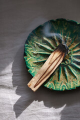 Burning palo santo stick on ceramic plate. Antistress and relaxation ritual concept
