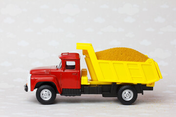 Toy dump truck delivering sand.   Transportation construction materials on building site.