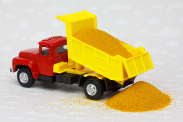 Sand delivery by dump truck. Toy truck pours the sand on the ground