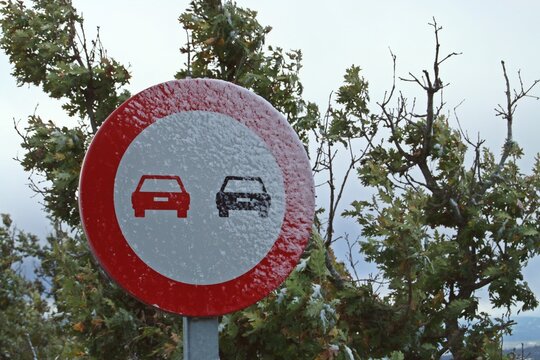 Se&ntilde;al de tr&aacute;fico de prohibido adelantar. Se&ntilde;al de tr&aacute;fico completamente helada tras la ca&iacute;da de una peque&ntilde;a nevada.