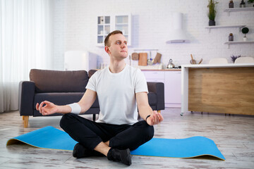 A man doing yoga exercises at home, sitting on the living room floor. Healthy lifestyle.