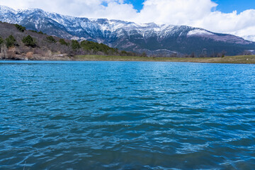 Blue water of a mountain lake and mountains in the distance covered with snow