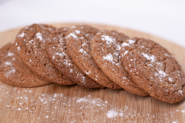 oatmeal cookies covered in powdered sugar on wooden stand board. sweet bakery concept