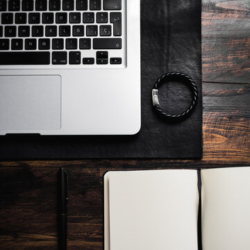 Laptop On Leather Desk Mat, Leather Bracelet, Notebook And Pen On Wood